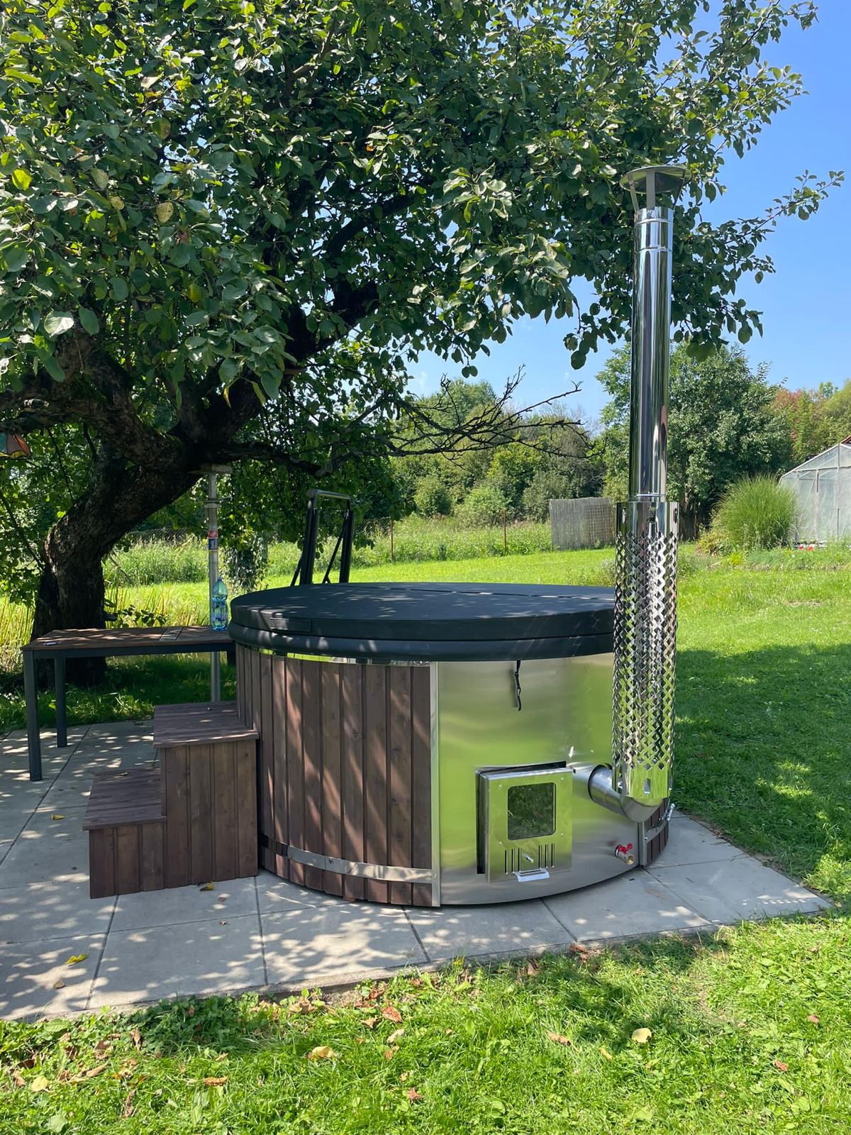 Runder Hot Tub mit Holzverkleidung und externem Holzofen im Garten