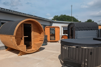 polarsauna shop Hot Tub 200 cm mit Holzverkleidung und Abdeckung neben Fasssaunen im Außenbereich