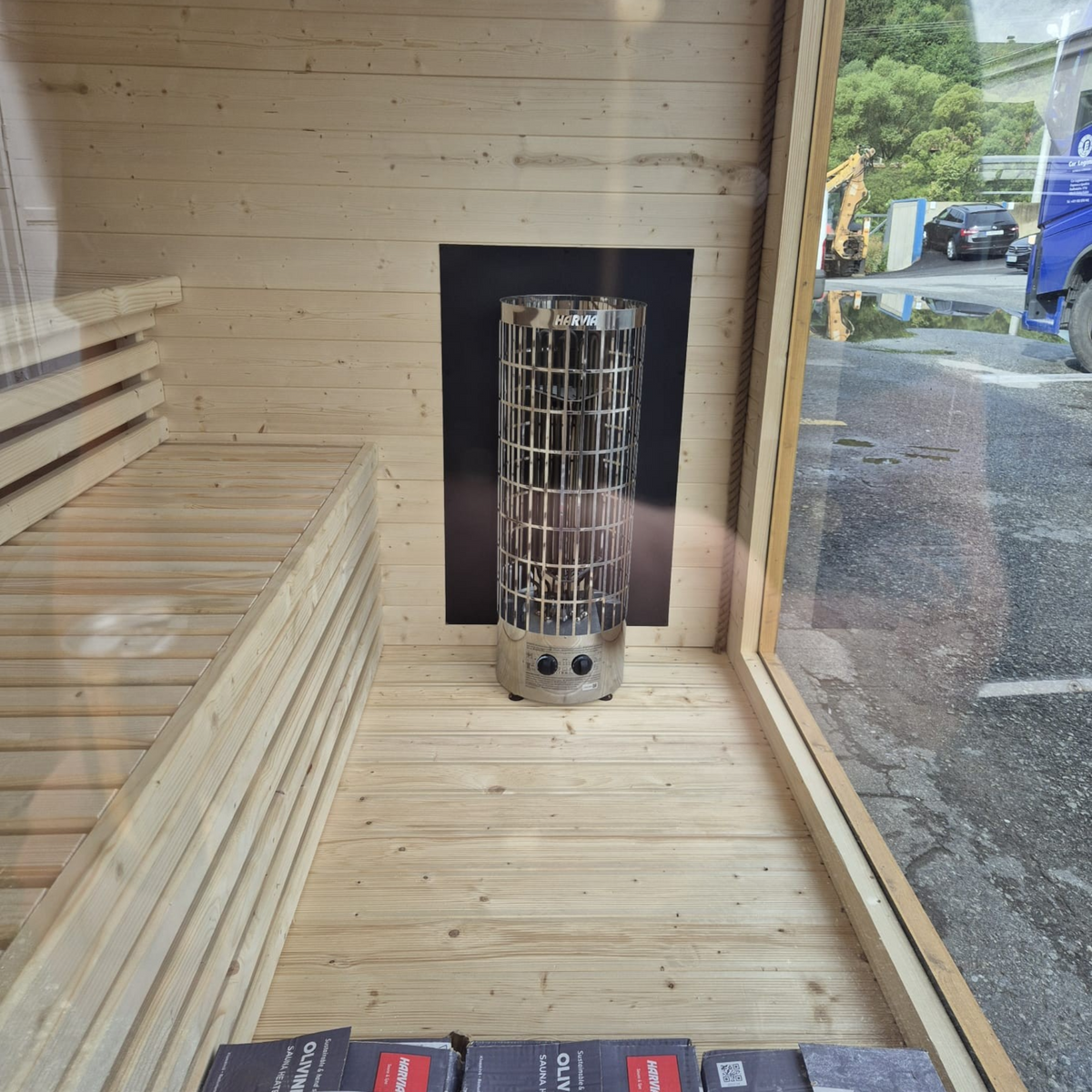 Innenansicht der polarsauna shop Saunahaus Highline M mit hellem Holz, Harvia Saunaofen und Panoramafenster