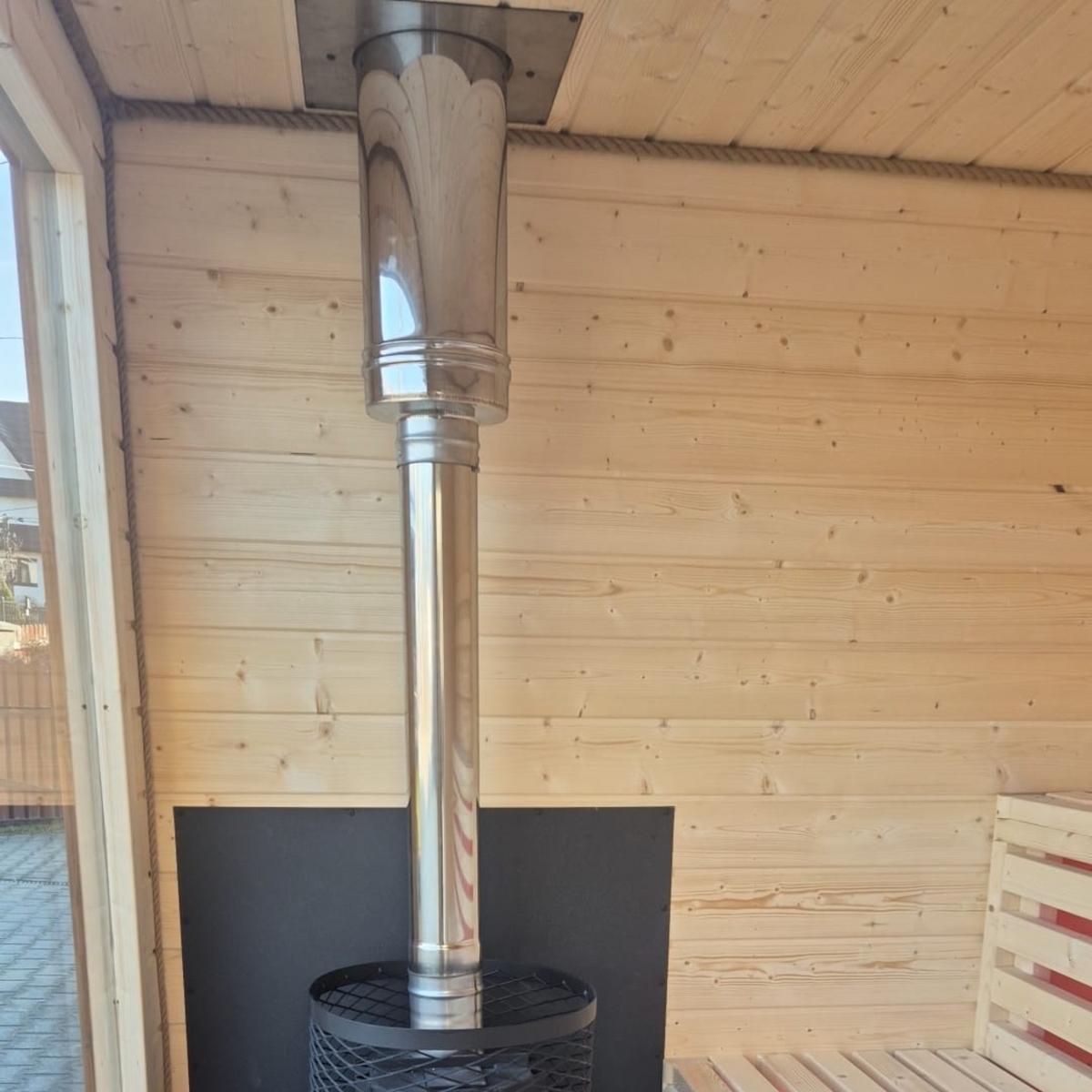 polarsauna shop Saunahaus Highline M Innenansicht mit schwarzem Saunaofen, Edelstahlrohr und hellen Holzsaunabänken