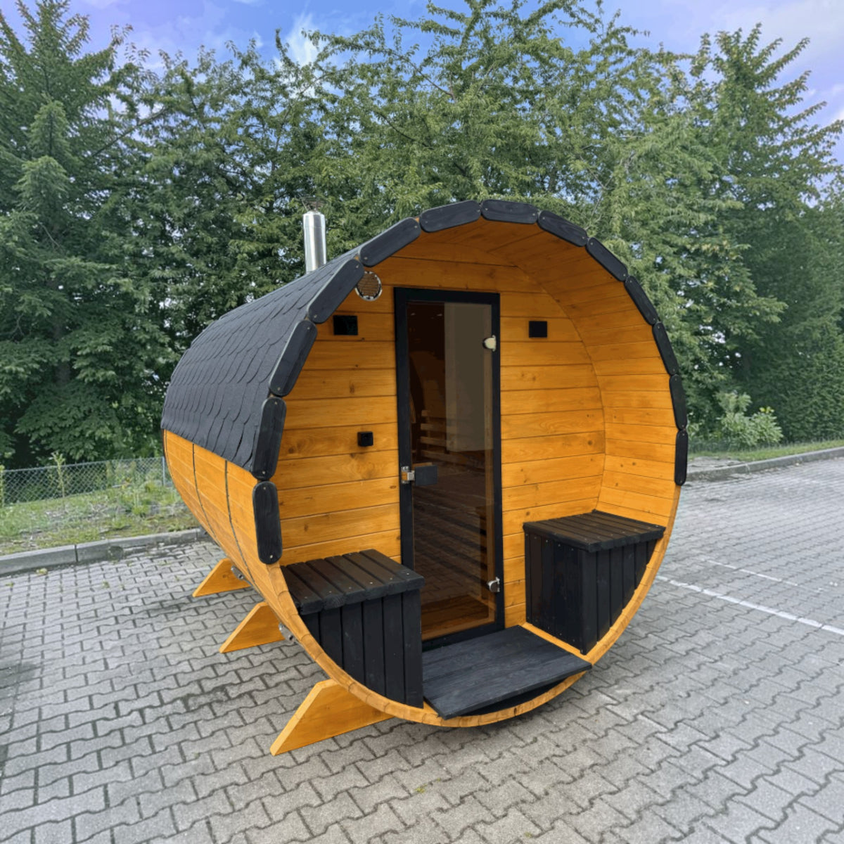 polarsauna shop Fasssauna Highline aus Fichtenholz mit schwarzem Dach und Glaseingangstür im Außenbereich