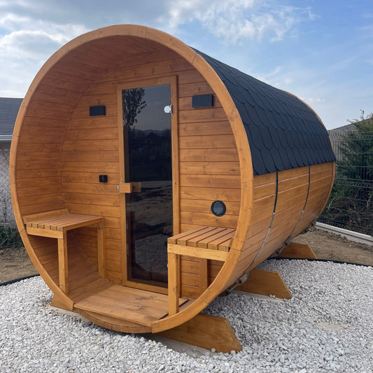 polarsauna shop Fasssauna Highline 285 aus Holz mit Terrasse, Glastür und schwarzem Dachschindelschutz im Garten