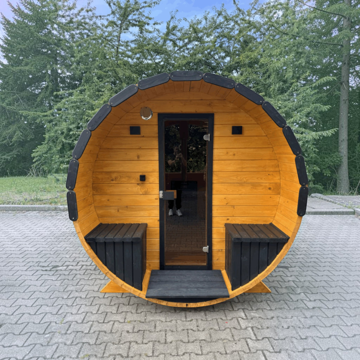 polarsauna shop Fasssauna Highline aus massiver Fichte mit 225 cm Durchmesser und schwarzer Akzentuierung im Garten