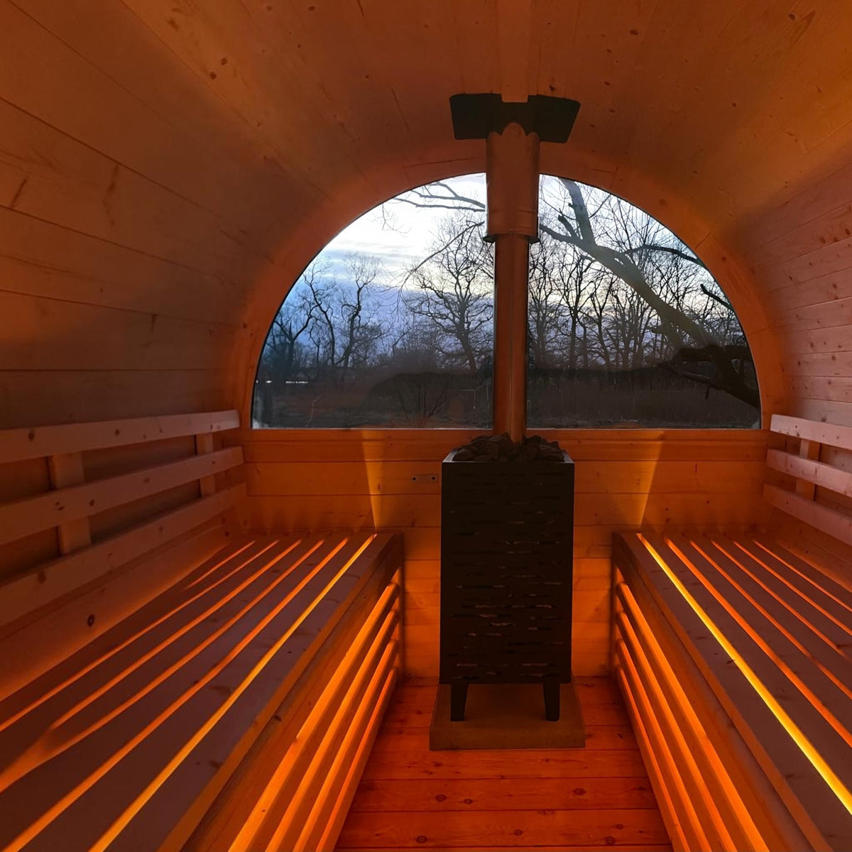 Innenansicht der polarsauna shop Fasssauna Highline mit Holzofen, Panoramafenster und indirekter LED-Beleuchtung