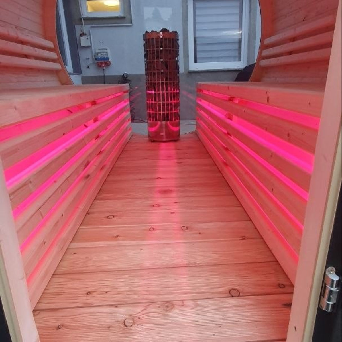 Innenansicht der polarsauna shop Fasssauna Highline 285 mit Holzsaunabänken, LED-Beleuchtung und Harvia-Saunaofen.