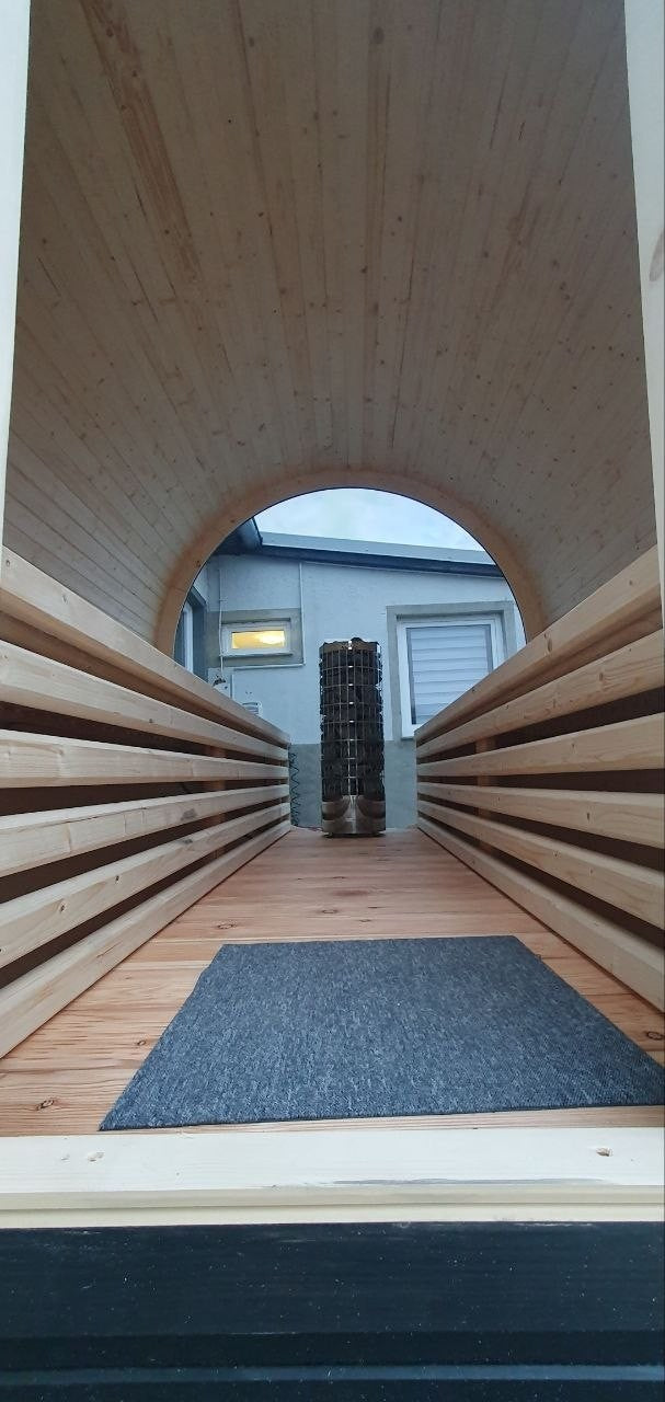Innenansicht der polarsauna shop Fasssauna Highline 285 mit Holzbänken, Bodenrost und Harvia Saunaofen