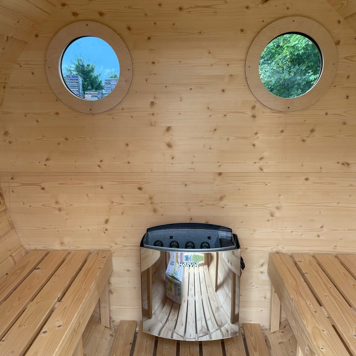 Innenansicht der polarsauna shop Fasssauna Trendline aus Fichtenholz mit Harvia-Elektroofen und zwei runden Fenstern