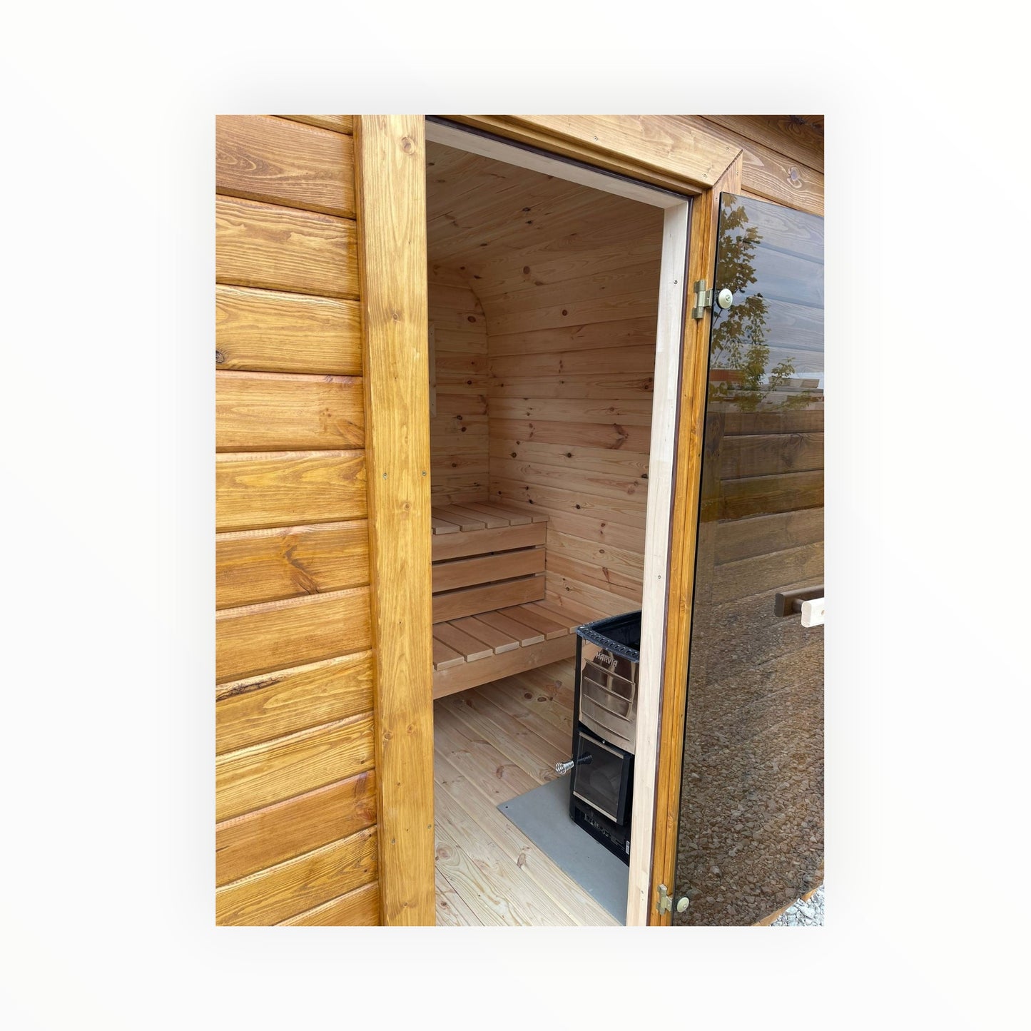 polarsauna shop Gartensauna aus hellem Holz mit Harvia-Ofen und Glastür für ein privates Wellness-Erlebnis im Garten