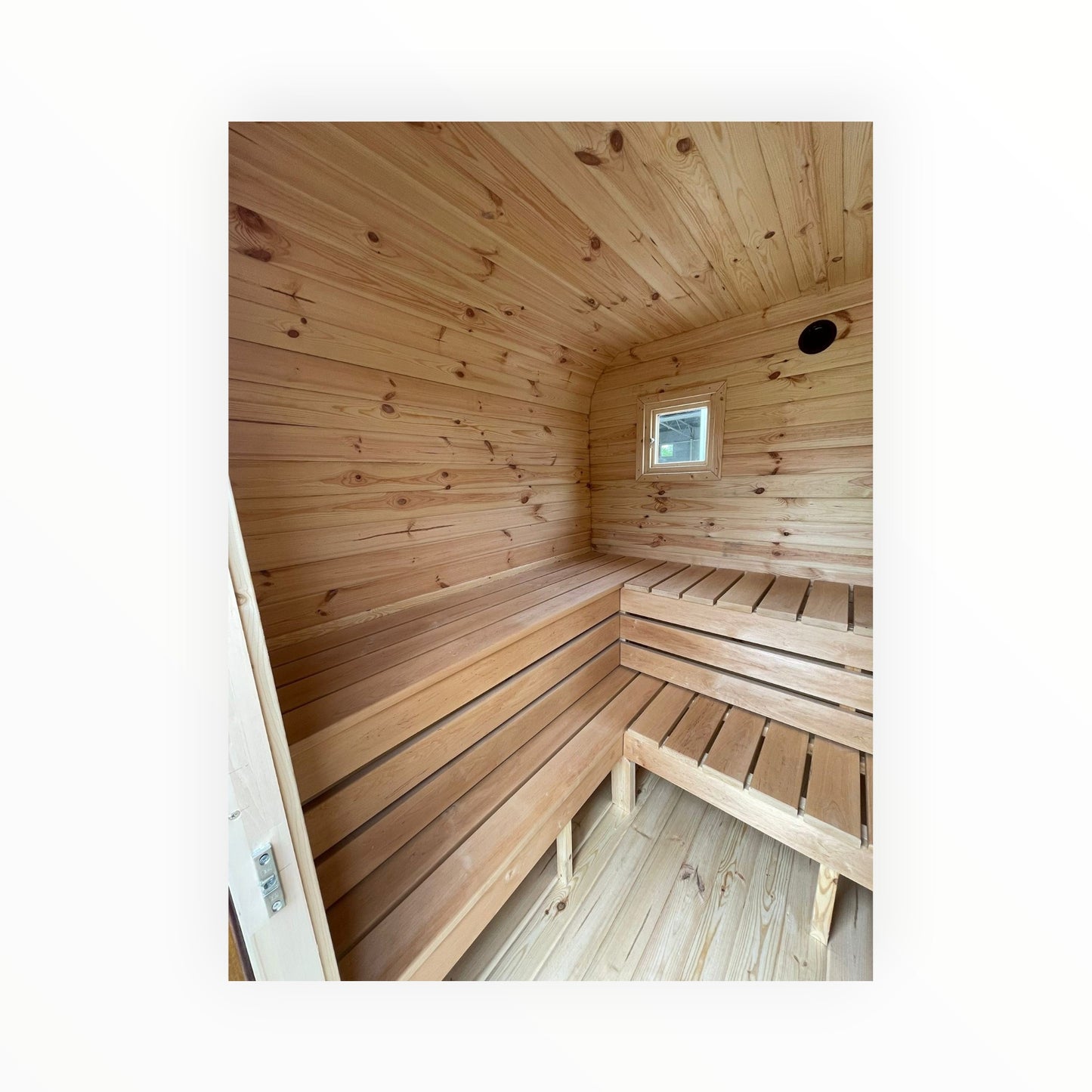 Innenansicht der polarsauna shop Gartensauna mit hellen Holzsaunabänken, Wandverkleidung aus Naturholz und Fenster.