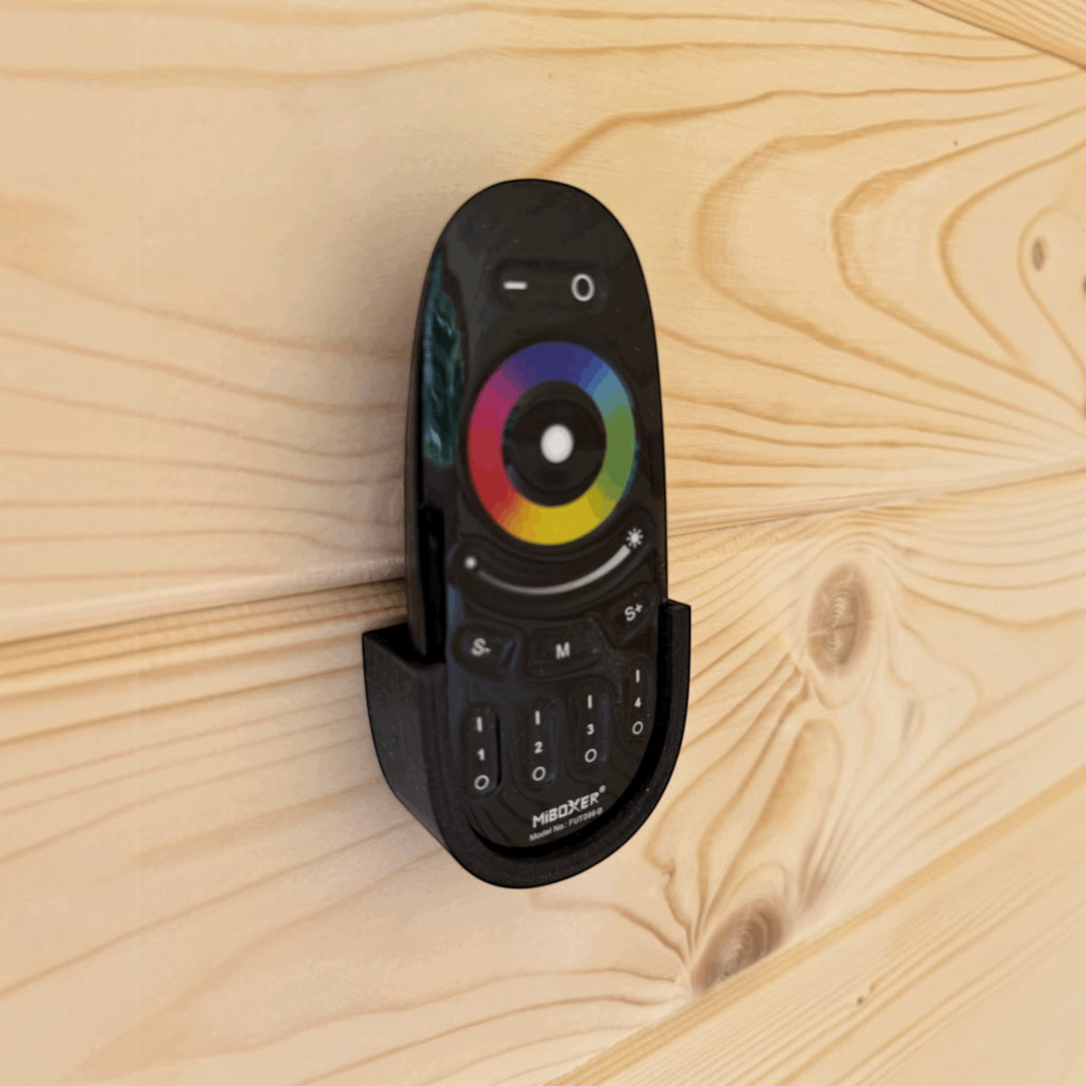 polarsauna shop Fernbedienung für LED-Beleuchtung in schwarzer Wandhalterung an einer hellen Fichtenholz-Saunawand