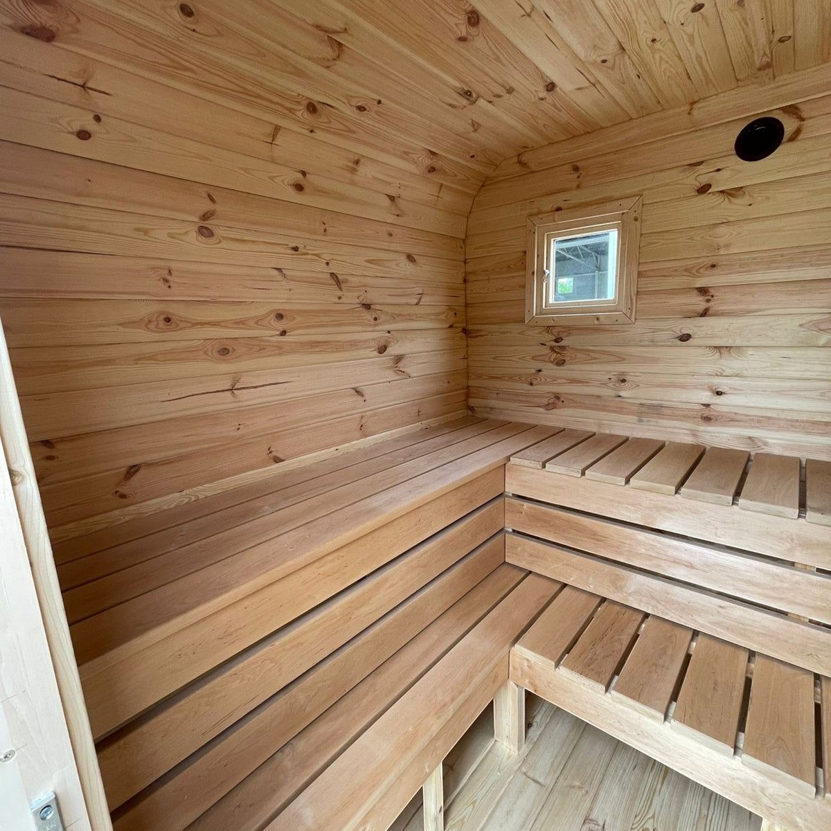 Innenansicht der polarsauna shop Quadro-Sauna 2M mit hellen Fichtenholz-Wänden, Eckbänken und kleinem Fenster.