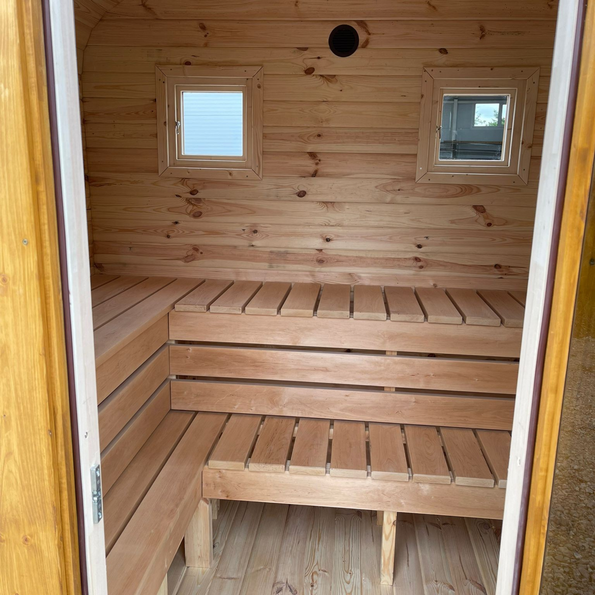 Innenansicht der polarsauna shop Quadro-Sauna 2M aus hellem Fichtenholz mit zwei Sitzbänken und zwei kleinen Fenstern