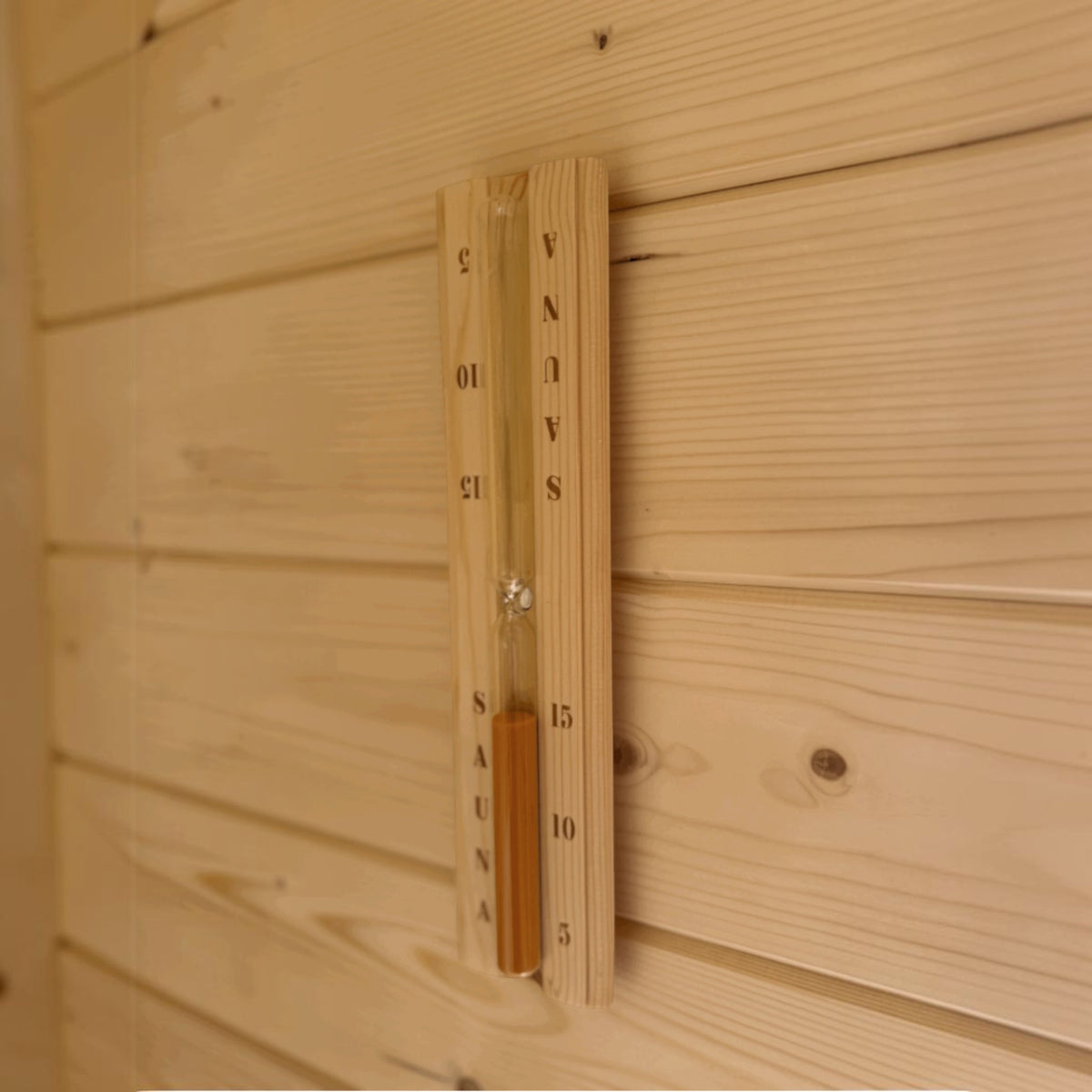 polarsauna shop Sanduhr aus hellem Fichtenholz an einer Saunawand montiert für die Fasssauna Highline