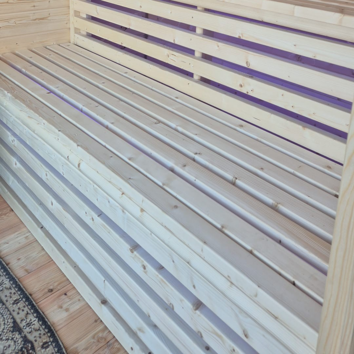 Innenansicht der polarsauna shop Saunahaus Highline M mit hellen Holzsaunabänken und integrierter LED-Beleuchtung